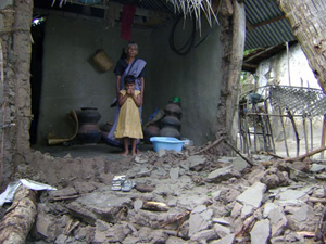 洪水により倒壊した家に立つ家族
