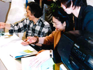 葉祥明と柳瀬が忙しそうに本にサインを書いている