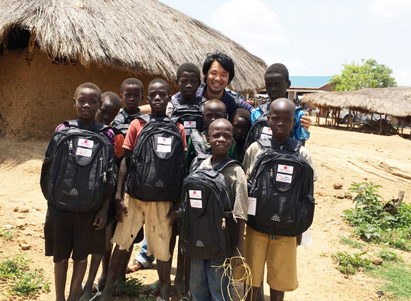 南スーダン難民の子どもたちと、駐在員の吉川。子どもたちは、AARが配付したカバンを持っています