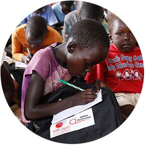 通学かばんをもらって勉強する南スーダン難民の子ども