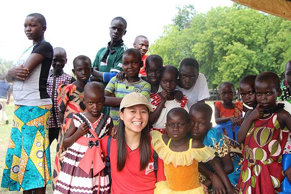 ウガンダで活動するAAR駐在員家高の周りには、10人以上の子どもたちがおり、カメラに向かって微笑んでいる