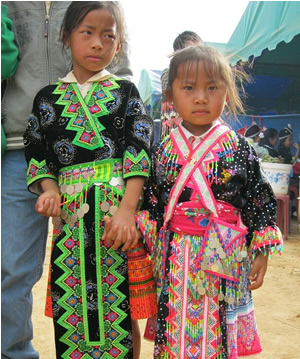 2人の女の子が、黒い色がベースの服を着ている。ピンクや黄緑などが使われた刺繍が、ジグザグ模様などにほどこされている