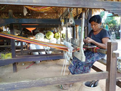 専用の木工品を用いてカラフルな糸で糸紡ぎをしている女性