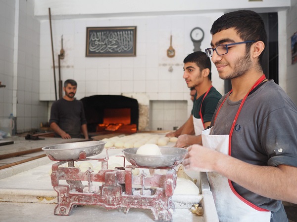 トルコのパン屋さんで働く青年たち、エプロンをしていてカウンターでパンの成型をしている。手が粉まみれ。