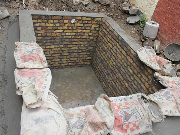 地面に掘った長方形の穴の四方にレンガのような素材が重ねられコンクリートで固められている