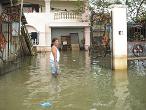 住宅前でひざまで水につかる女性