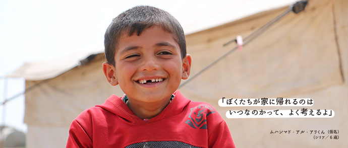 シリアの男の子が難民キャンプでほほ笑んでいる