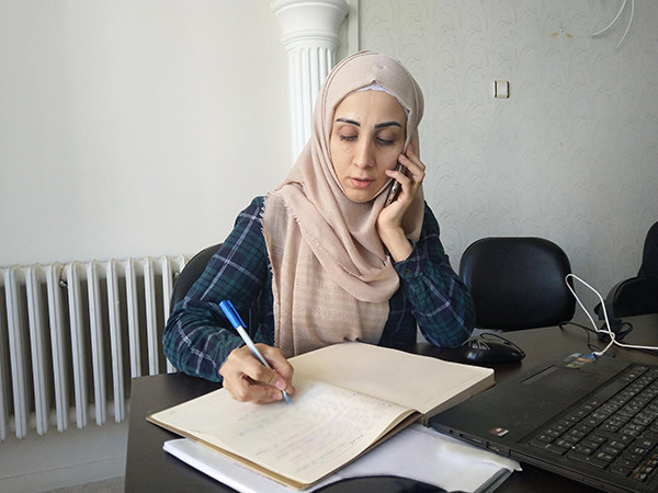 AARの事務所で難民の方に電話をかけながらメモを取るAARトルコ事務所スタッフ