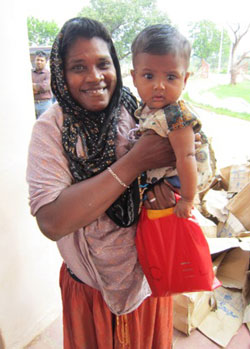 子どもを抱いて笑顔を見せる被災者の女性