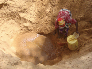 季節河川で水を汲む女性