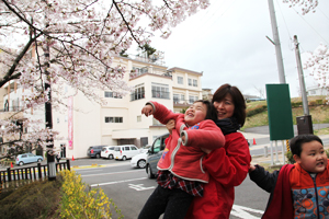 桜を見上げて笑顔の子どもたちとピアニストの山崎明子さん