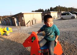 仮設住宅の敷地に設置された遊具で遊ぶ男の子