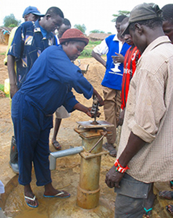 郡役所職員が井戸を修理する様子を７人から8人ほどの村人が見守っています。