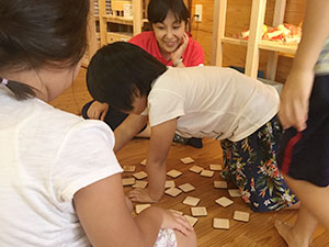 木製の神経衰弱カードで遊ぶ子どもたちとAARの田中晴子