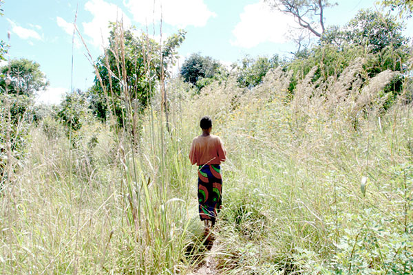 アンゴラ女性が広大な草原で1人ポツンと立っている　後姿