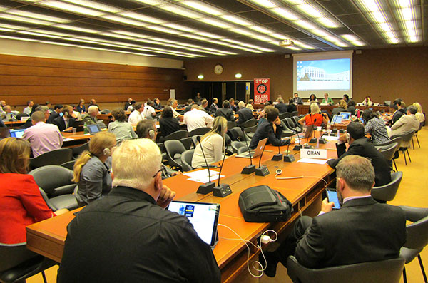 前方で、発表者がスクリーンを利用して話している　会場は長机がいくつも並んでいて、それぞれパソコンなどを利用しながら参加している