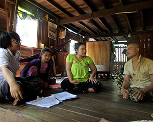 木製の床板に4人があぐらをかいて座っている　中央2人は女性　右端と左端は男性