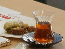 中央がくびれた形が特徴的な小ぶりの細いグラスに入れた熱い紅茶と、ピスタチオやデーツを使ったお菓子