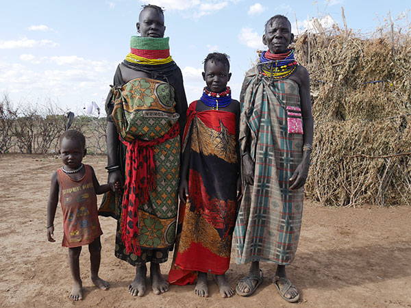 4人のトゥルカナ民族が並び、そのうちの一人は子どもで手をつないでいる。アフリカの伝統的な布をまとっている。