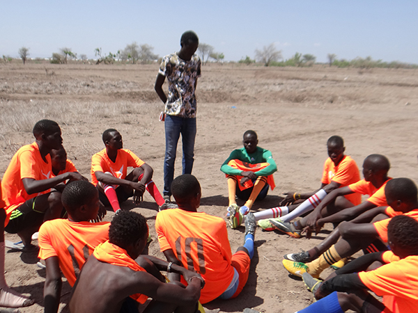 ユニホームを着た難民と地域住民の人々　サッカーの休憩中に戦略を練っている
