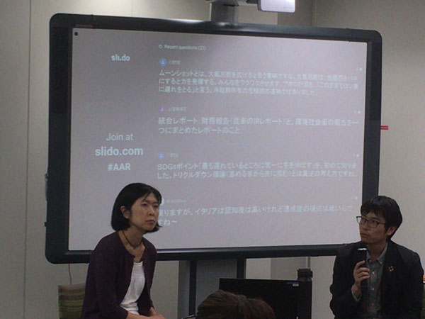 木下氏と星野氏が大きな画面の前に座っている。画面には参加者からの質問が文字で表示されている
