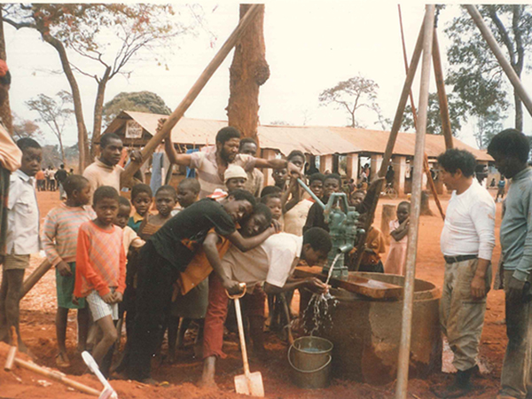 子どもを含む30名のザンビア人が井戸に集まり、井戸水を飲んでいる