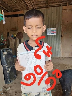 男の子が両手で紙を持ち、紙をこちらにむけて立っている。画像には赤い文字が加工されて書かれている。