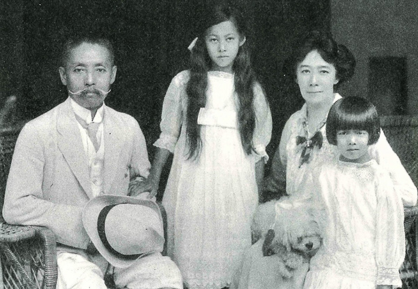 家族写真　尾崎行雄はスーツ姿にハット帽を手にしている　母と姉、本人も洋装でドレスを着飾っている