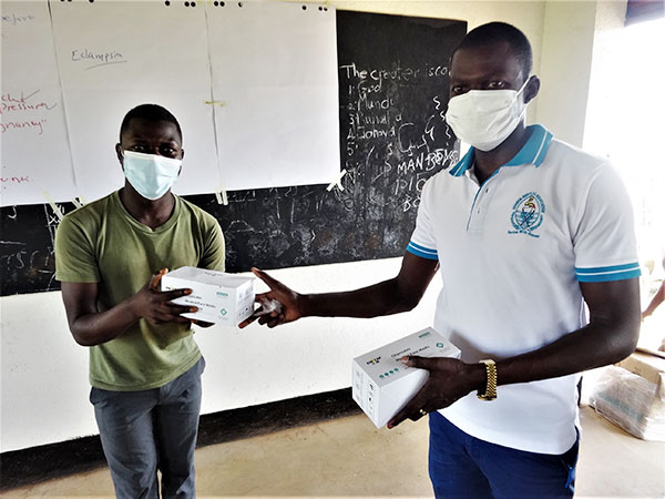 スタッフからコンゴ難民の男性がマスクが入った箱を受け取っている