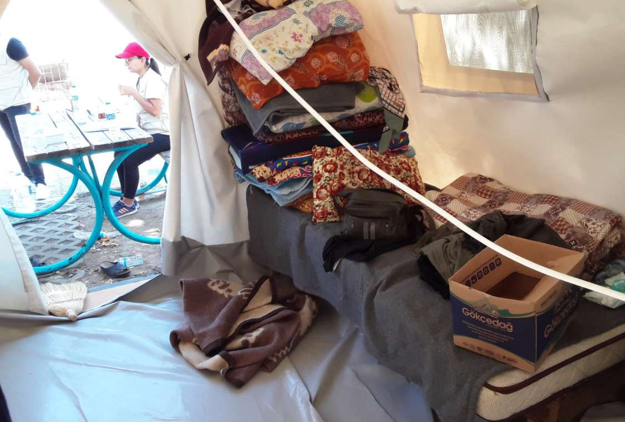 Inside the tent, a photo of a bed piled with clothes