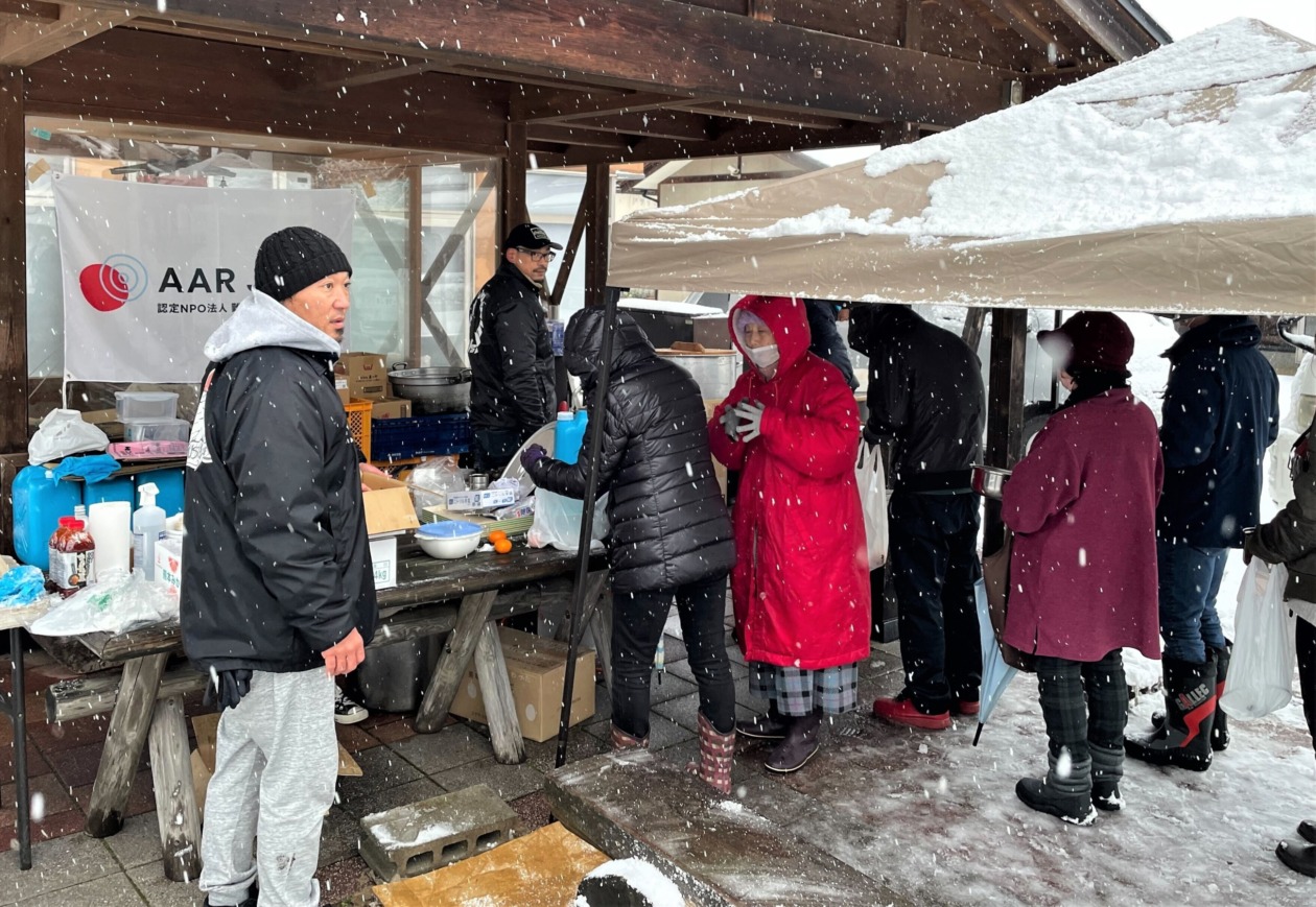 People lined up for the soup kitchen in the snowy weather.