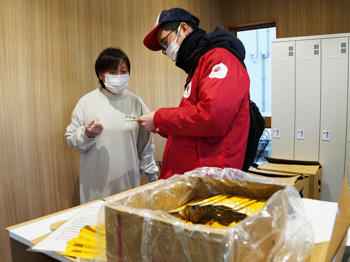 A woman receives honey in a tube from an AAR staff member