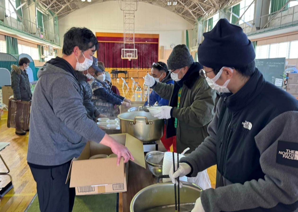 People with kitsune udon noodles in the gymnasium of an elementary school that serves as an evacuation shelter.