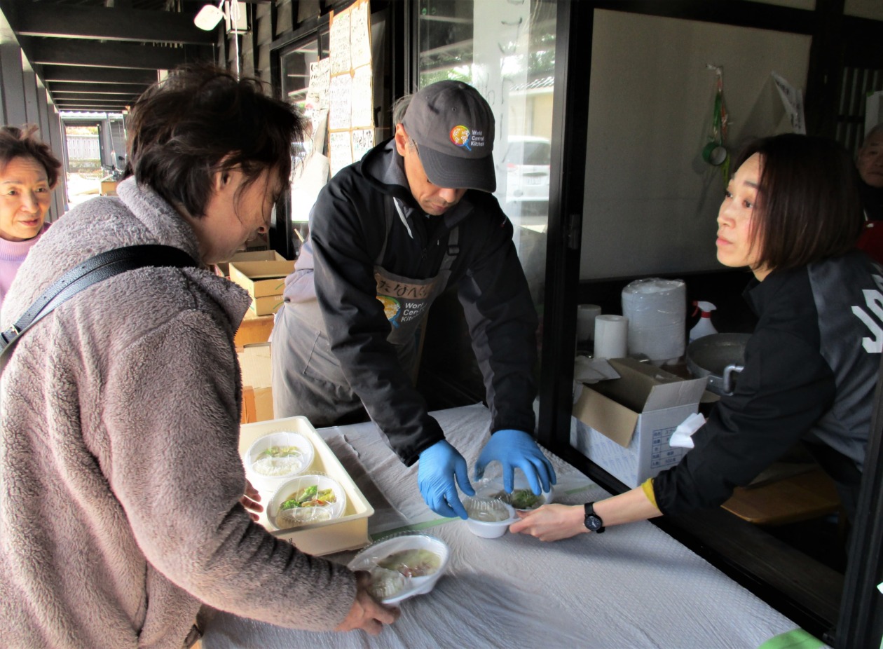 A staff member giving cooked meals to a woman