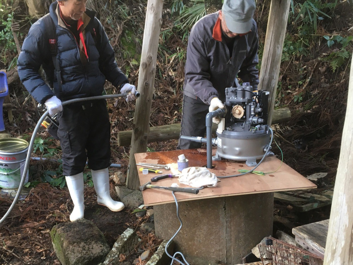 Two men installing a pump on a well.