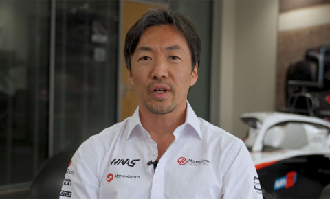 The MoneyGram Haas F1 Team Principal Mr. Ayao Komatsu standing in front of a racing car.