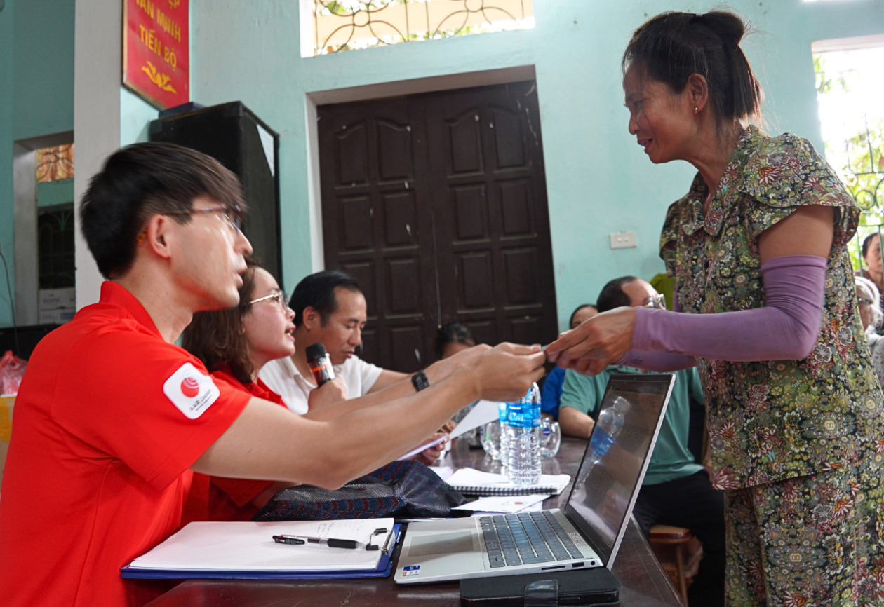 A seated AAR staff member hands money to a woman