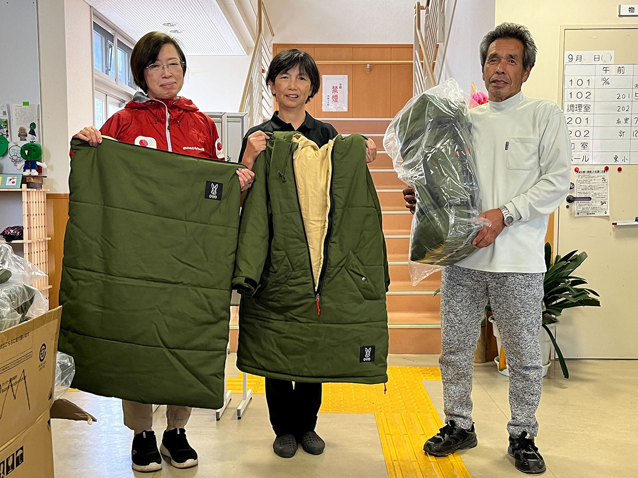 Two women and a man standing with outerwear in their hands