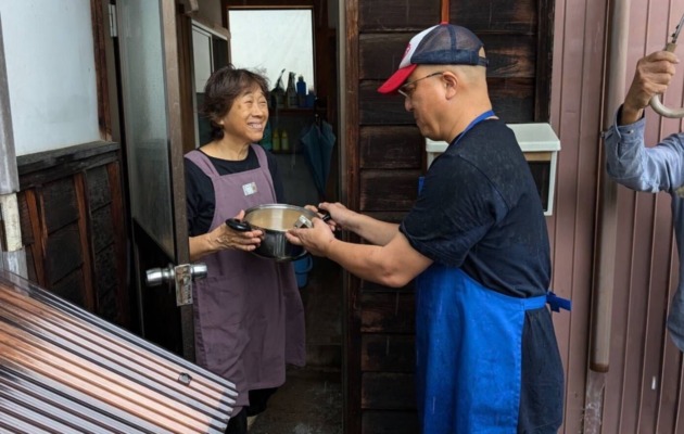 A man handing out food and a woman receiving it at the entrance