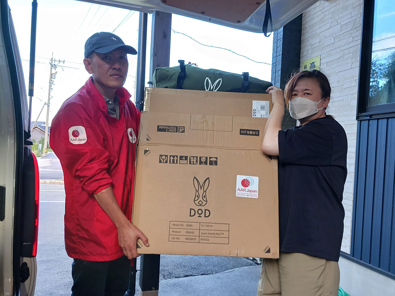 A car on the left, an AAR staff member on the right, and a woman from the facility standing with a cardboard box