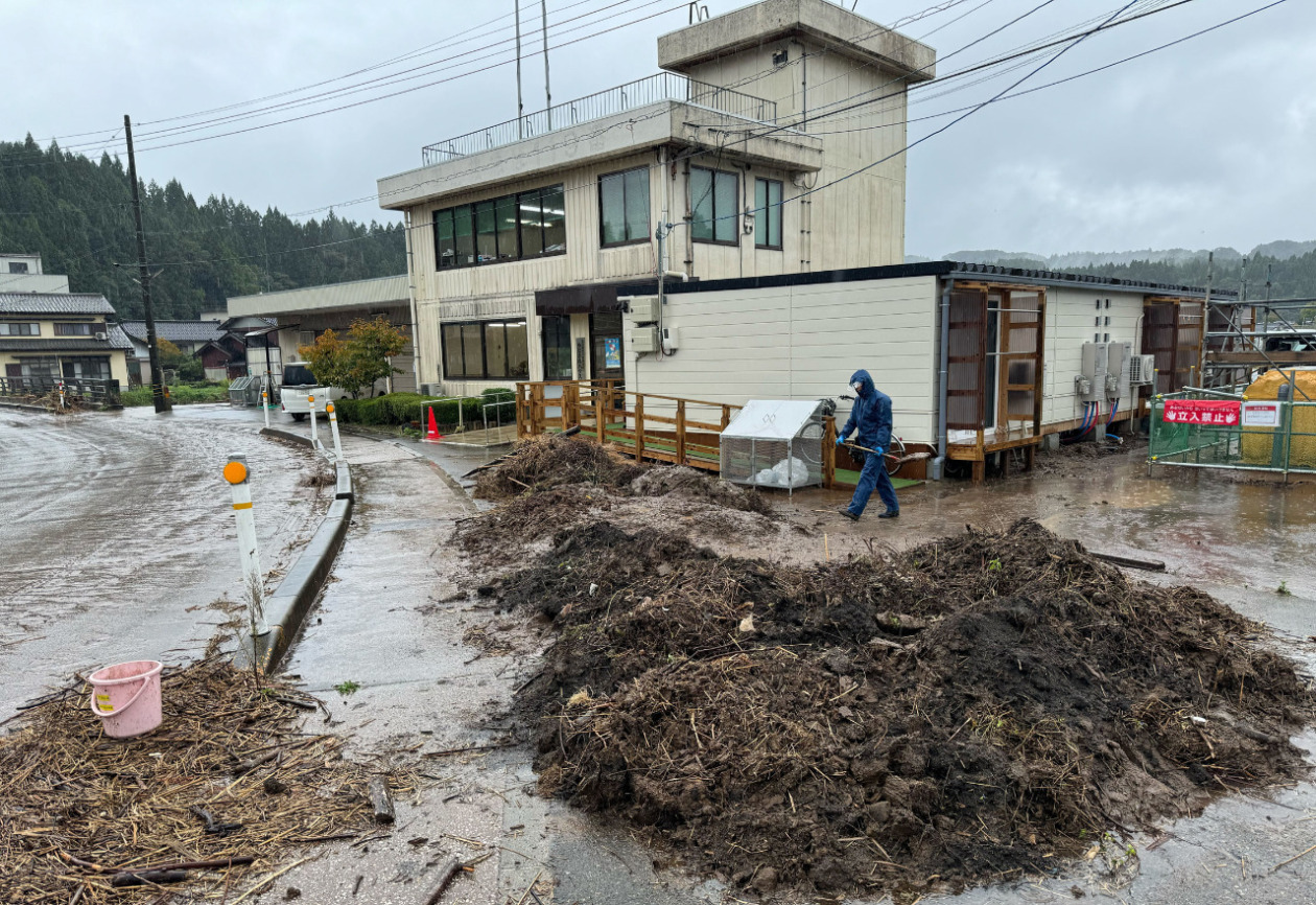 A man shoveling mud and a pile of mud