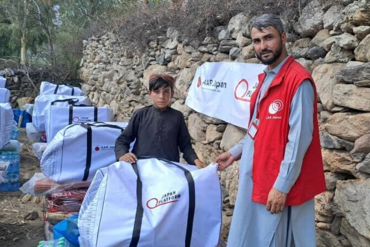 A boy is carrying a large white bag