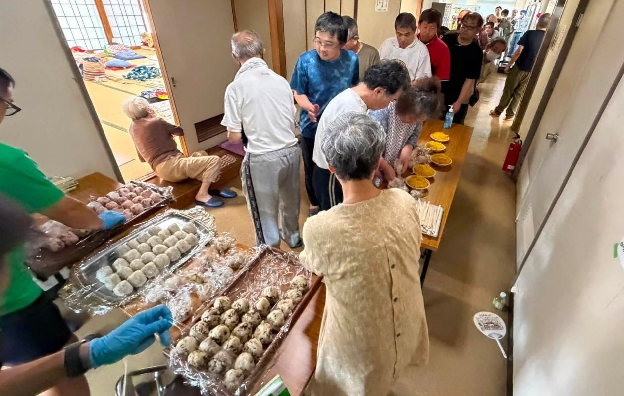 Rice balls prepared on a table and evacuees are lining up for distribution
