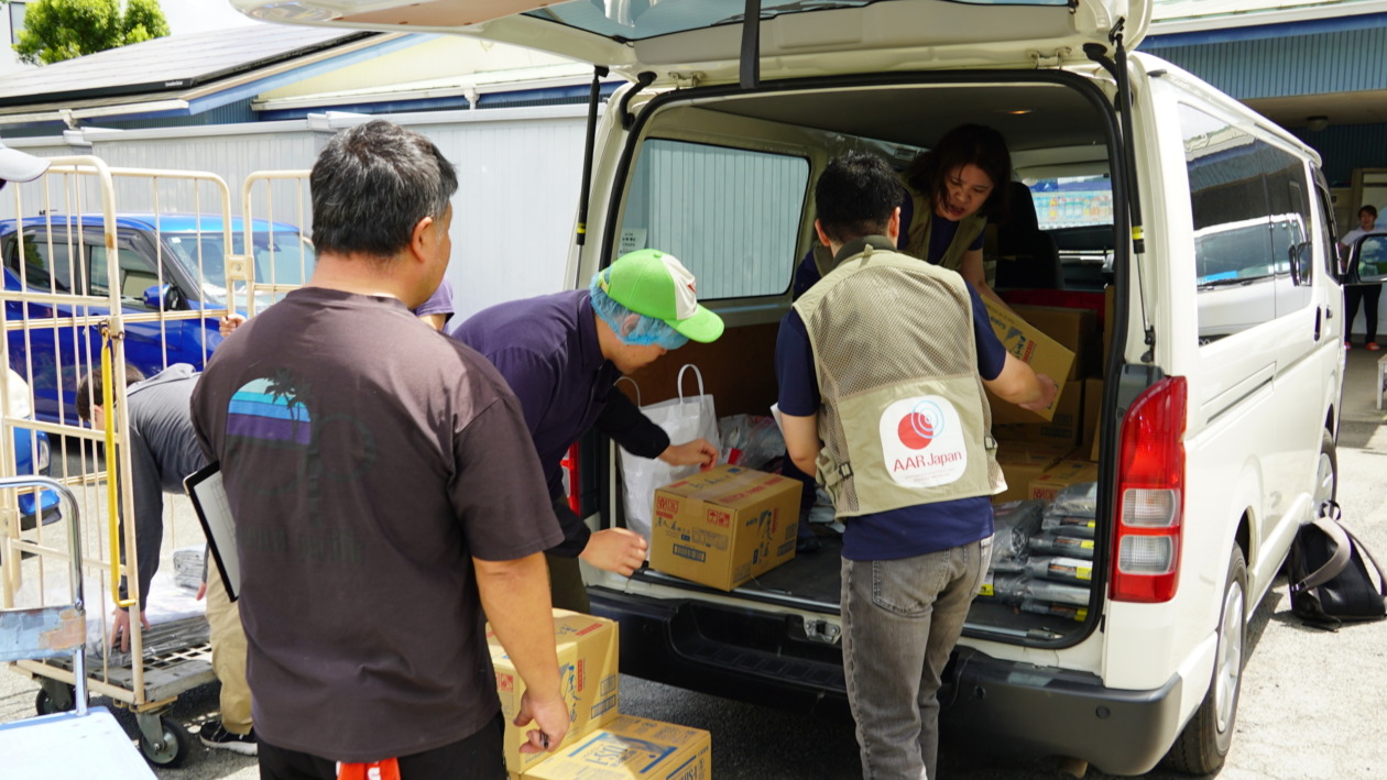 Some men and women loading supplies into a car
