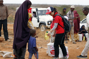 ケニアで親子連れに支援物資を手渡す難民を助ける会の職員