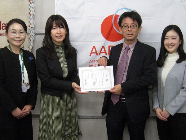 AARのロゴを前に目録手にしたパルシステム東京佐藤さま、AAR堀江を中央に4人が並んでいる。