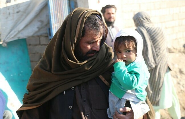 父親が困った顔をして幼い子どもを抱いている写真