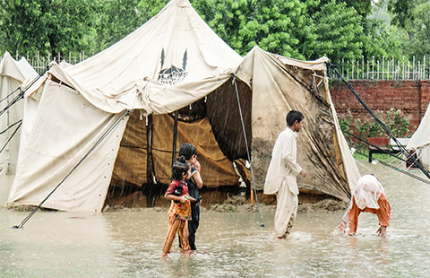 洪水によって水につかってしまったテントと、その前で立っている子どもたち