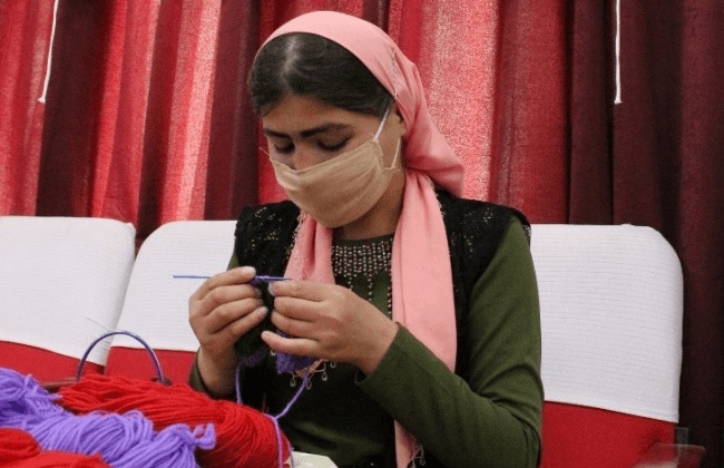 女性が毛糸を使って編み物をしている