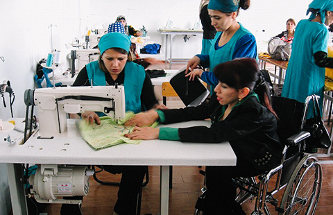 ミシンを使った裁縫の仕方を教わっている女性二人とそれを指導する女性の写真